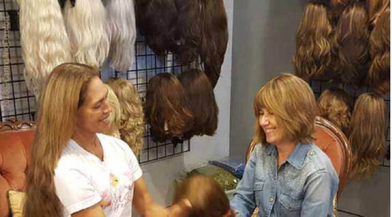 Wig maker showing human hair wig to customer